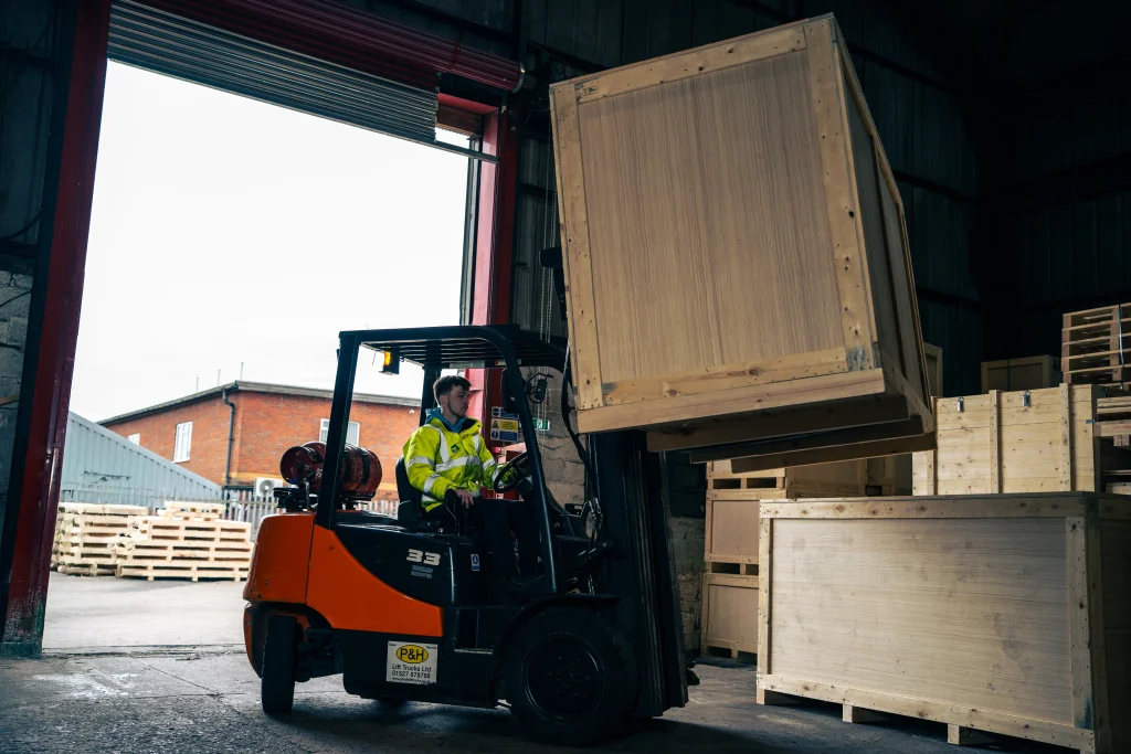Forklift moving a bespoke timber export case in warehouse.