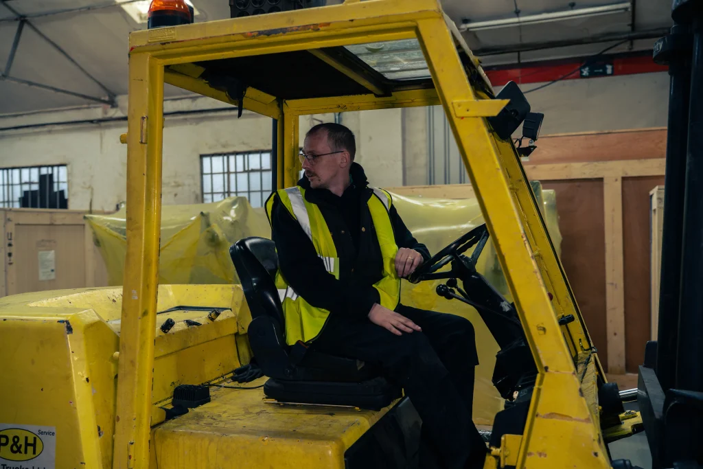 IM Export Services forklift operator handling timber export cases inside warehouse.