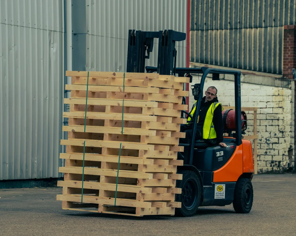 Forklift moving stacked timber pallets at IM Export Services.