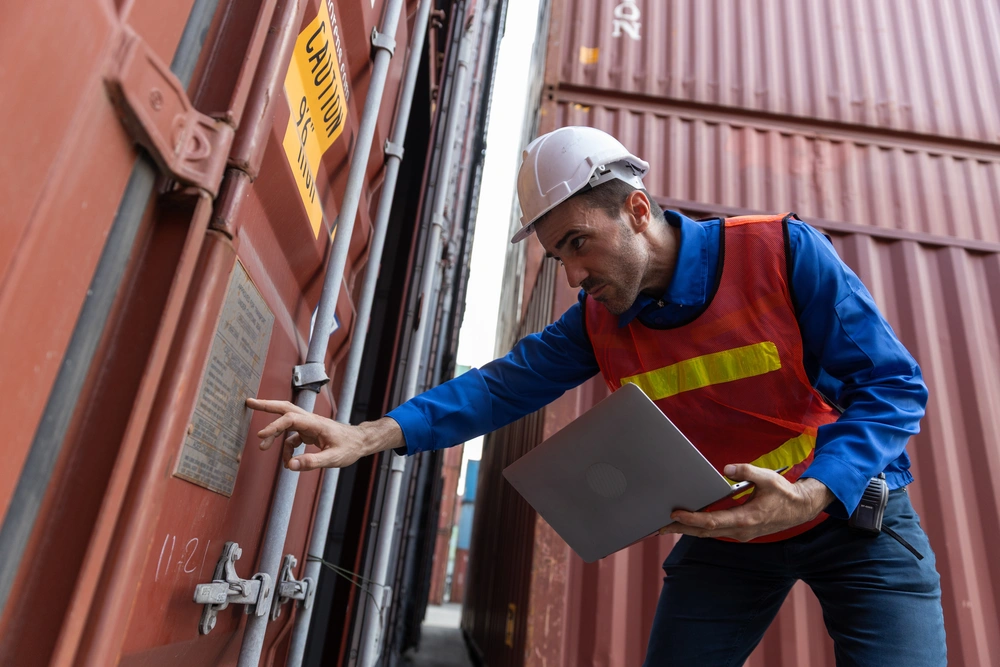 Worker in safety clothing inspecting shipping container documentation.