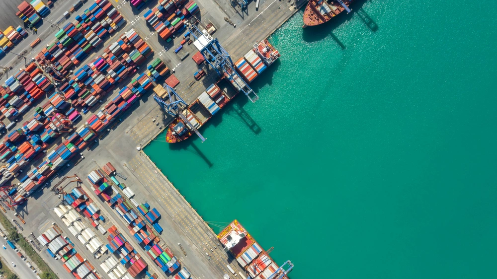 Aerial view of a cargo ship and shipping containers in a port.